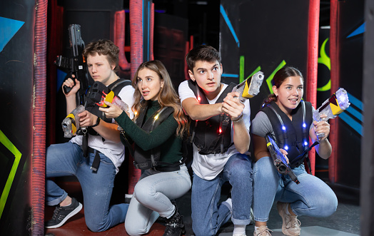 Four people with lasertag guns squatting in arena