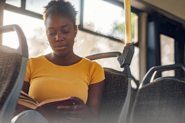 femme afro-américaine dans un bus et lisant un livre - circonscription photos et images de collection