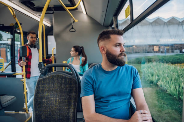 uomo seduto vicino alla finestra e guardando altrove mentre guida in un autobus - transportation bus mode of transport public transportation foto e immagini stock