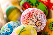 Colorful traditional Easter eggs with floral ornaments, origami decorations and crewel wool, close-up view.