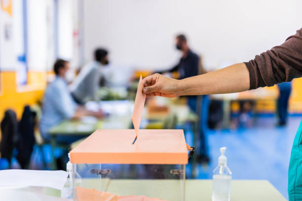 elezioni della comunità autonoma di madrid. referendum democratico per il voto del governo. mano in posa di una busta in un'urna elettorale per le elezioni comunitarie - scelta foto e immagini stock