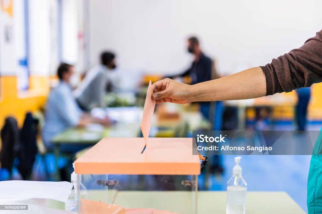 Autonomous community of Madrid elections. Democraty referendum for government vote. Hand posing an envelop in a ballot box for community elections Madrid voting for elections of the community for government. hand voting in a poll Voting Stock Photo
