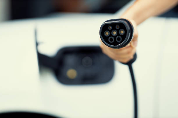 istock Progressive idea of focus hand pointing charging plug at camera, blur background 1474023140