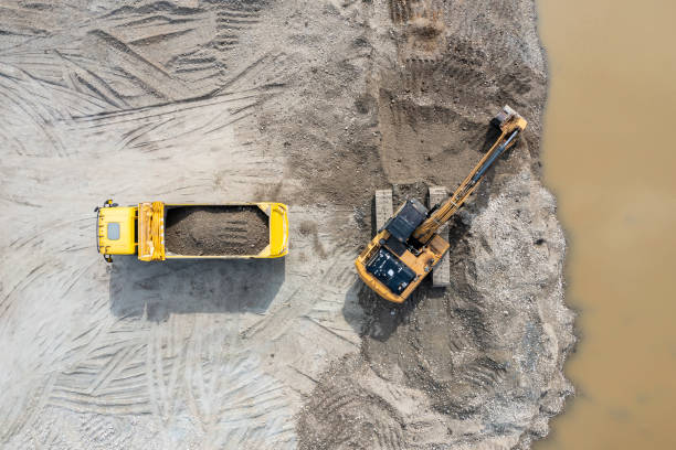 砂と砂利ピットでのダンプトラックと掘削機 ストックフォト