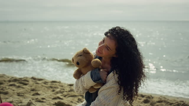 Latina woman posing sea beach. Gorgeous lady modeling holding teddy bear outside