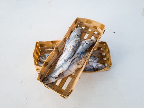Raw pindang fish in a bamboo container on a white background