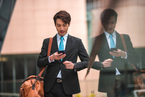 istock Busy Chinese Man Using his Cellphone while Carrying a Small Bag 1474029280