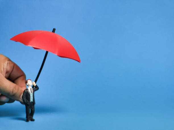 istock Businessman miniature with hand holding red umbrella. 1474030918