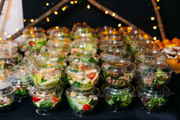 Many portions of various salads with meat and vegetables in plastic serving dishes with lids. atering serving portions of salads on the table. Buffet food indoor in luxury restaurant. stock photo
