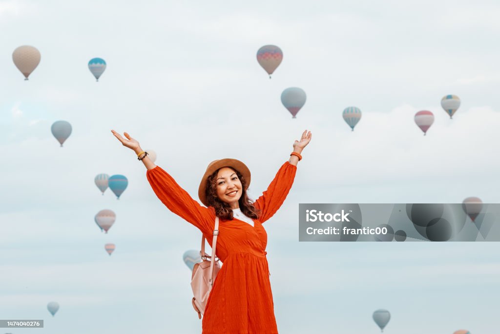 The sun shone down on the girl as she observed air balloons drift away. She wearing a gorgeous red dress 30-34 Years Stock Photo