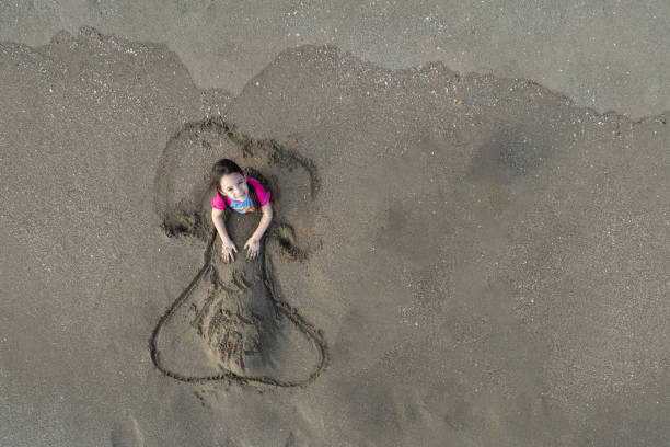 счастливый ребенок, играющий с песком на пляже - central america flash стоковые фото и изображения