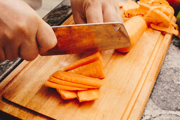 istock Woman slicing carrots on bamboo cutting board on granite kitchen countertop 1474042496