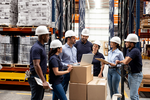 Latin American business manager talking to a group of employees at a distribution warehouse - staff meeting concepts