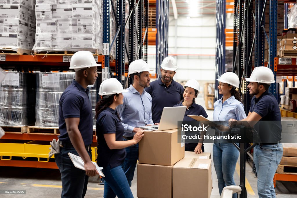 Business manager talking to a group of employees at a distribution warehouse Latin American business manager talking to a group of employees at a distribution warehouse - staff meeting concepts Supply Chain Stock Photo