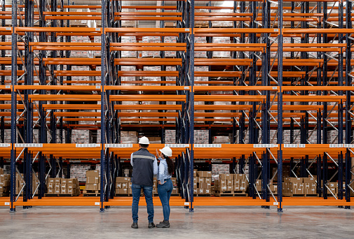 Rear view of a team of employees supervising the operation of a distribution warehouse - global business concepts