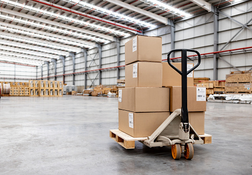 Pallet jack moving boxes at a distribution warehouse - global business concepts