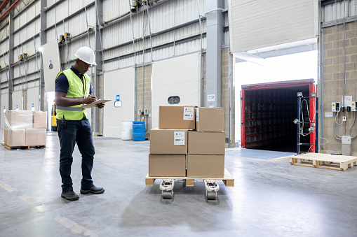 Operator working at a distribution warehouse loading boxes on a truck for shipping - freight transportation concepts