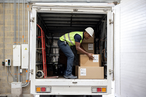 African American operator loading boxes on a truck at a distribution warehouse - freight transportation concepts