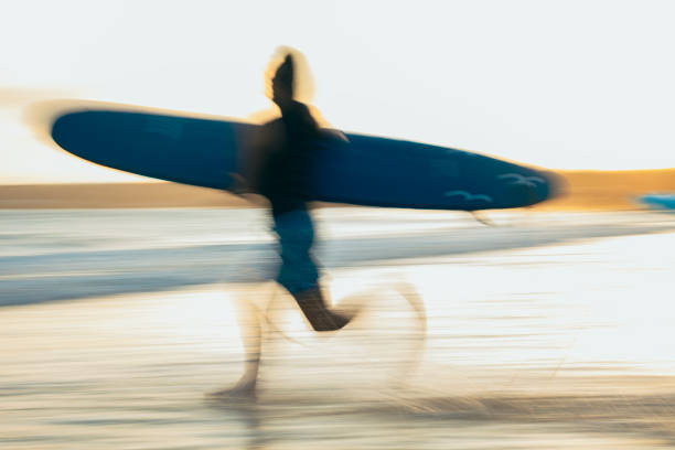 fearlessly charging into the waves, asian surfers are enjoying the good times of their holiday to the fullest. - longboarding surfing bildbanksfoton och bilder