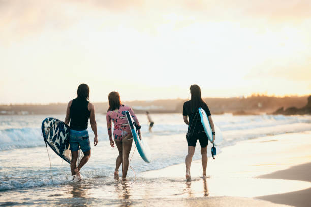 istock Three Asian surfing enthusiasts have finished surfing and are walking forward with their surfboards in hand. 1474048189