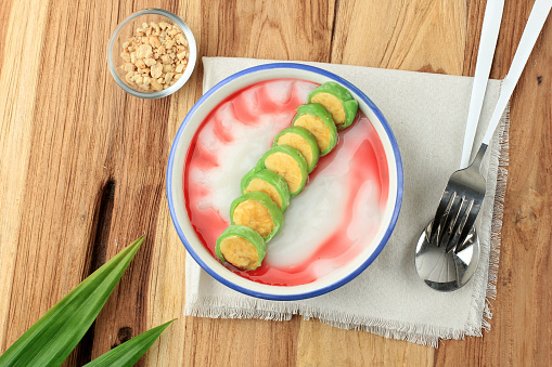 Es Pisang Ijo, Ripe Banana Rolled with Green Thin Crepes. Served with Rice Porridge and Red Syrup. Traditional Dessert from Makassar, South Sulawesi, Indonesia. Top View