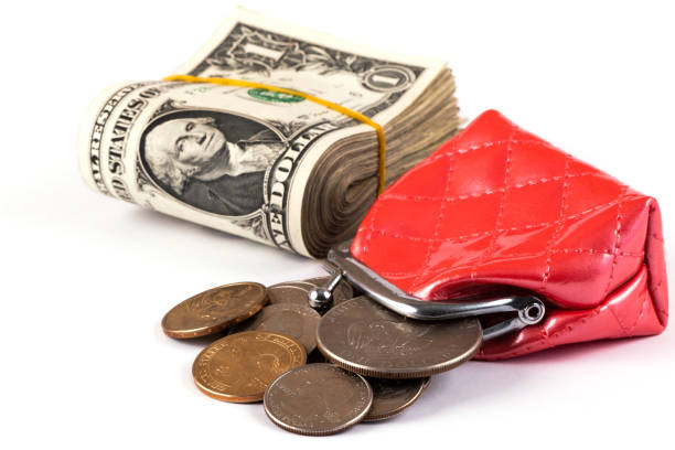 A stack of 1 american dollar bills, a red wallet and american coins on a white background