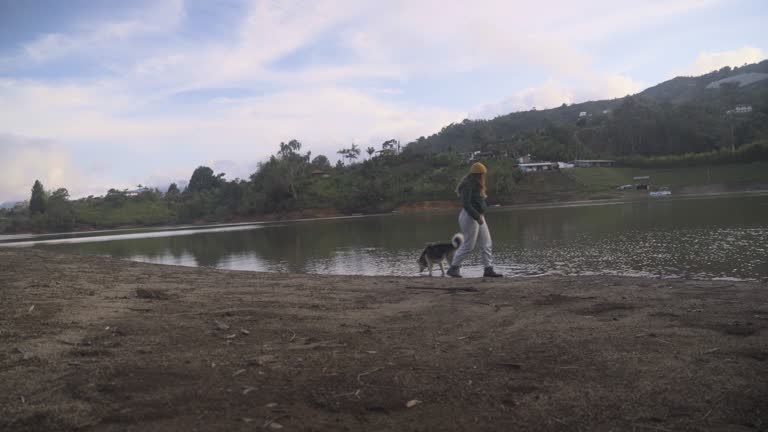 Young woman playing with her pet next to the lake in Peñol Colombia stock video