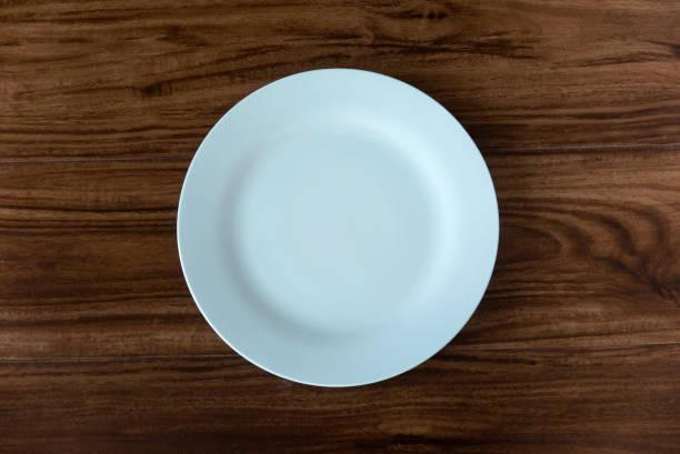 istock Top view of empty white plate on a wooden background. Flat lay, copy space. 1474058968
