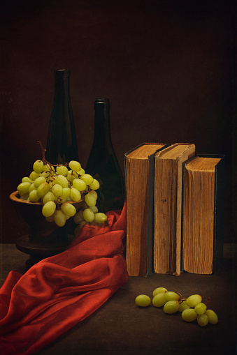 Still life with grapes, old books and bottles