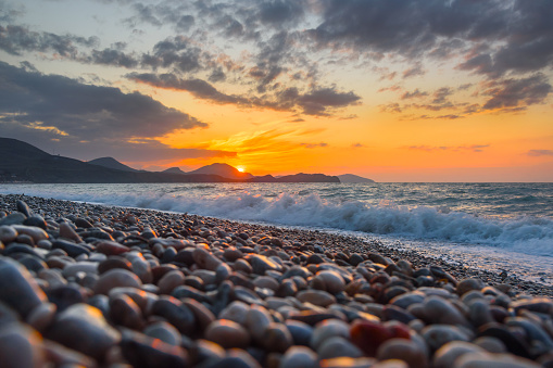 Sea coast with stones at sunrise. Beach of Black sea in Koktebel. crimea