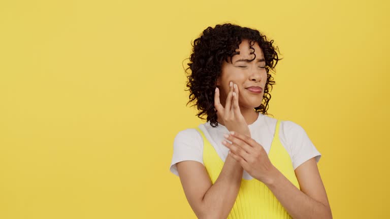 Black woman, face and toothache, mouth pain with dental and healthcare for teeth isolated on yellow studio background. Gum disease, cavity and mockup space, young female hands with hurt and injury