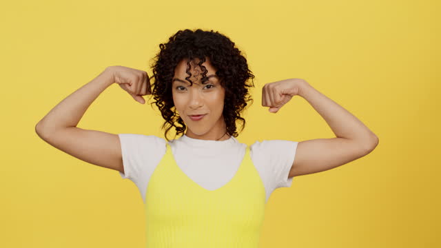 Model, face or strong arm on isolated background in empowerment, motivation or human rights strength on yellow mock up. Smile, portrait or woman flexing muscle or kissing bicep in winner studio pride