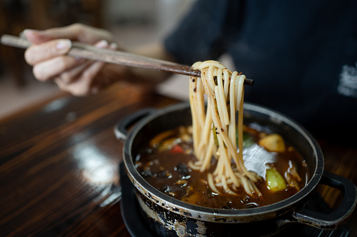 Crop shot of Asian lady having spicy Chinese homemade noodle with chopstick close up