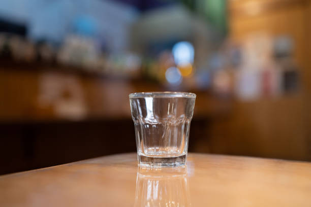 istock Small empty glass on wooden table with blur background 1474073945