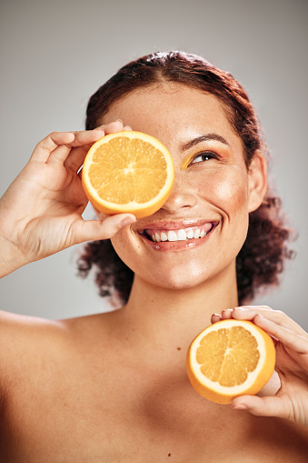 Orange, beauty and woman face in studio with a smile for natural skin glow, cosmetic and dermatology. Facial results, health and wellness of aesthetic model person happy with vitamin c fruit idea