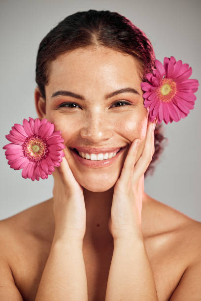 Flowers, skincare and face portrait of a woman with natural beauty and a smile for dermatology. Facial, wellness and self care for skin glow, nature cosmetics or makeup of a healthy model in studio flores, cuidado de la piel y retrato facial de una mujer con belleza natural y una sonrisa para dermatología. facial, bienestar y cuidado personal para el brillo de la piel, cosméticos de la naturaleza o maquillaje de un modelo saludable en el estudio