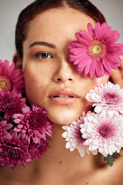 woman, flowers and studio portrait for beauty, wellness and skincare with spring aesthetic by background. model, girl and carnation plant with cosmetic health, natural skin glow and symbol for growth - nature beauty women fashion model imagens e fotografias de stock