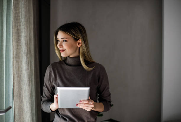 Happy woman manager holding tablet and standing