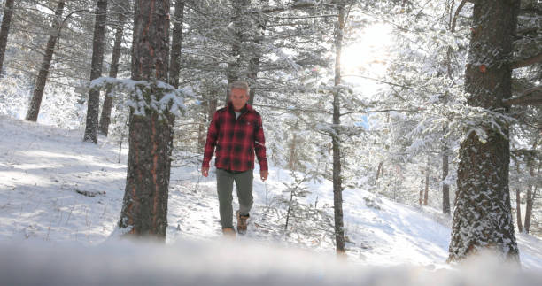 istock Mature man walks along snowy path in mountain  setting 1474076924