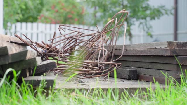 Remains of boards and iron bars after construction on a private plot, smooth camera movement