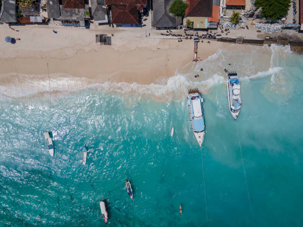 Aerial shoreline view of Jungutbatu beach at Nusa Lembongan Aerial shoreline view of Jungutbatu beach at Nusa Lembongan with tourist speedboat anchored. One of travel destinations close to Bali island, Indonesia. bali boat tour stock pictures, royalty-free photos & images