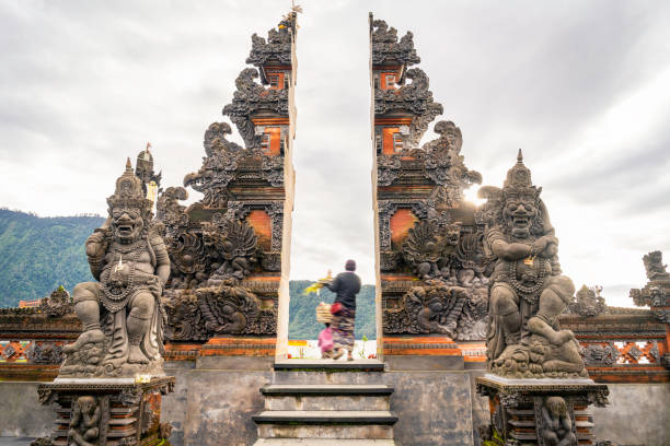 Balinese women in traditional costume passing through the gate of  temple on Bali, Indonesia