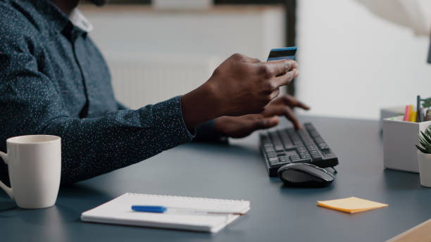 Close up of african american man hands typing credit card info on computer keyborad Close up of african american man hands typing credit card info on computer keyboard, online internet shopping leisure activity time. Business payment with web technology. Buying purchase transactions keyborad stock pictures, royalty-free photos & images