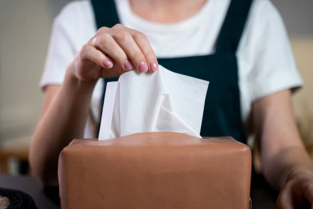 a woman's hand lifting tissue paper from a napkin box on the dining table - tissue box flu virus kleenex imagens e fotografias de stock