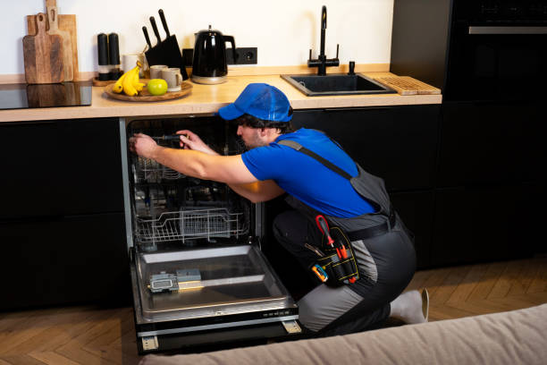 istock Young man in uniform with a set of tools repairs a dishwasher in the kitchen 1474092256