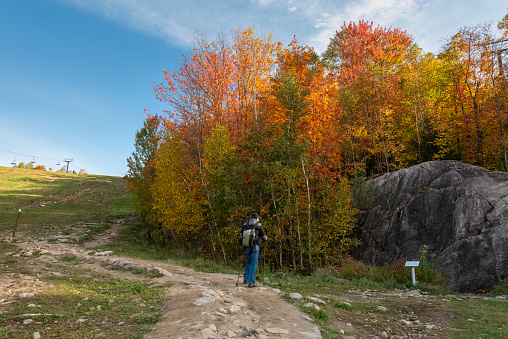Tourist reading the sign on Mount Tremblant track in autumn. Quebec. Canada.