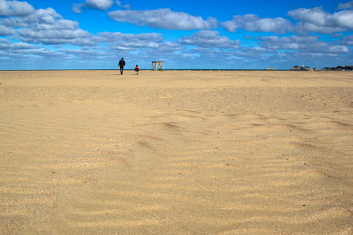 Man with son walking on the sand desert and blue cloudy sky