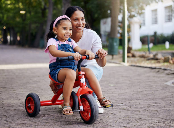 istock Mother, little girl and bicycle teaching with training wheels for learning or practice at the park. Happy mom helping child to ride her first bike with smile for proud playful moments in the outdoors 1474099309