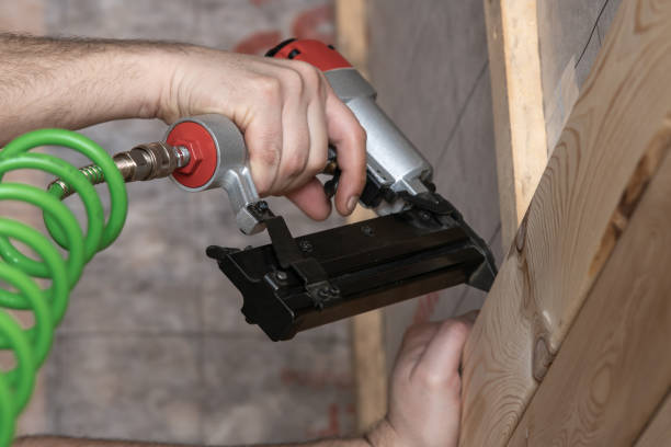 istock Unrecognizable cropped male hands using pneumatic nailer, nail gun with spiral cable for wooden timber board. Metal clip 1474100534