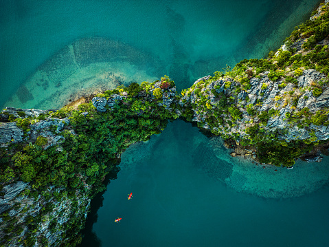 Drone view on rocks and canoes floating on turquoise water in the Halong Bay, Vietnam